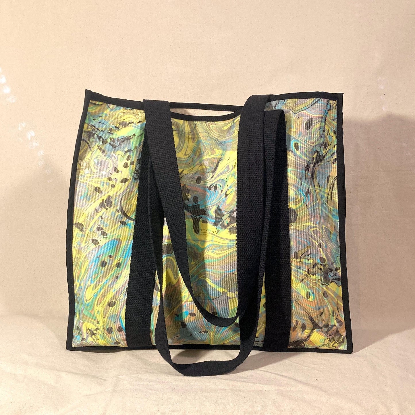 An oversized water marbled tote bag with contrasting straps