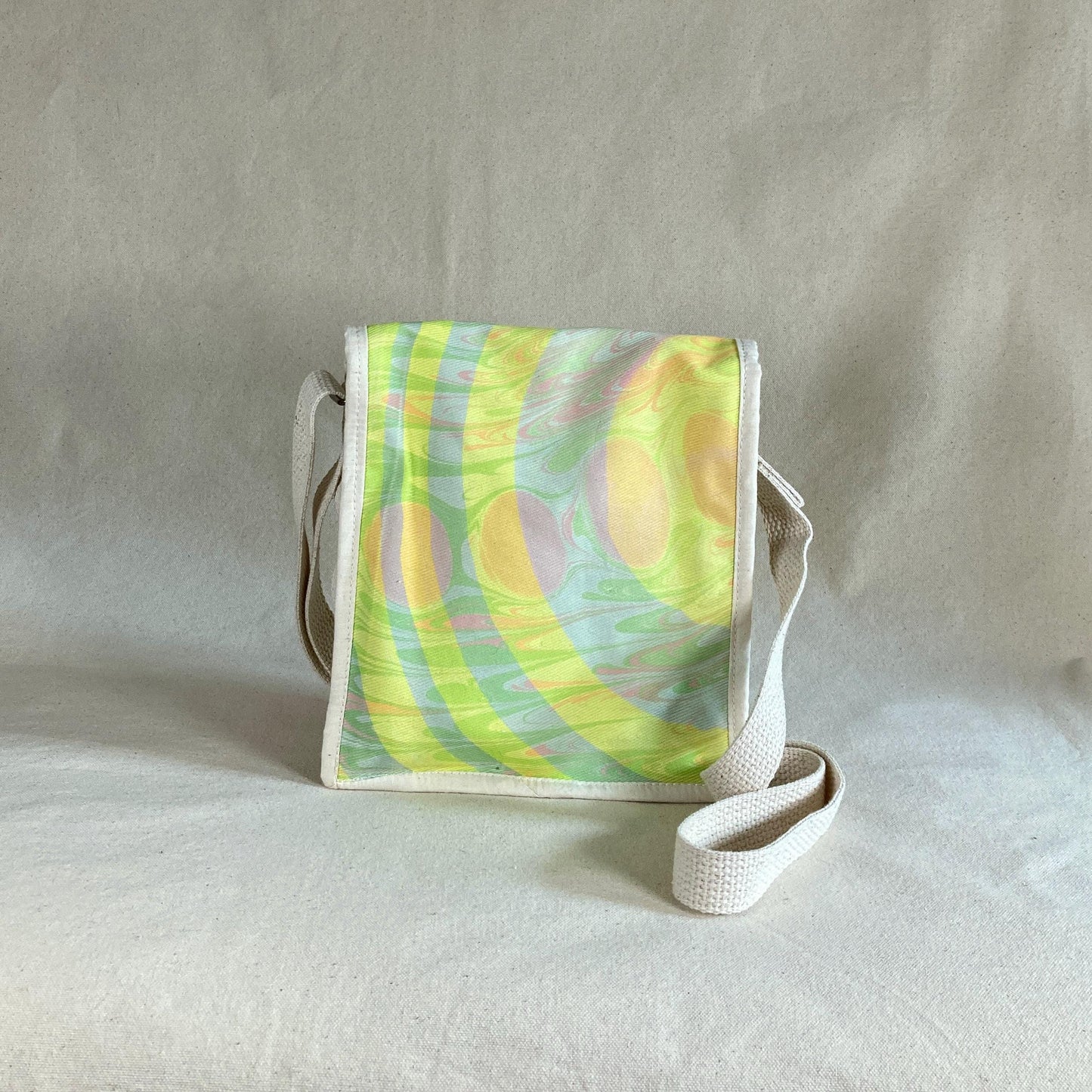 The back of a water marbled miniature messenger bag