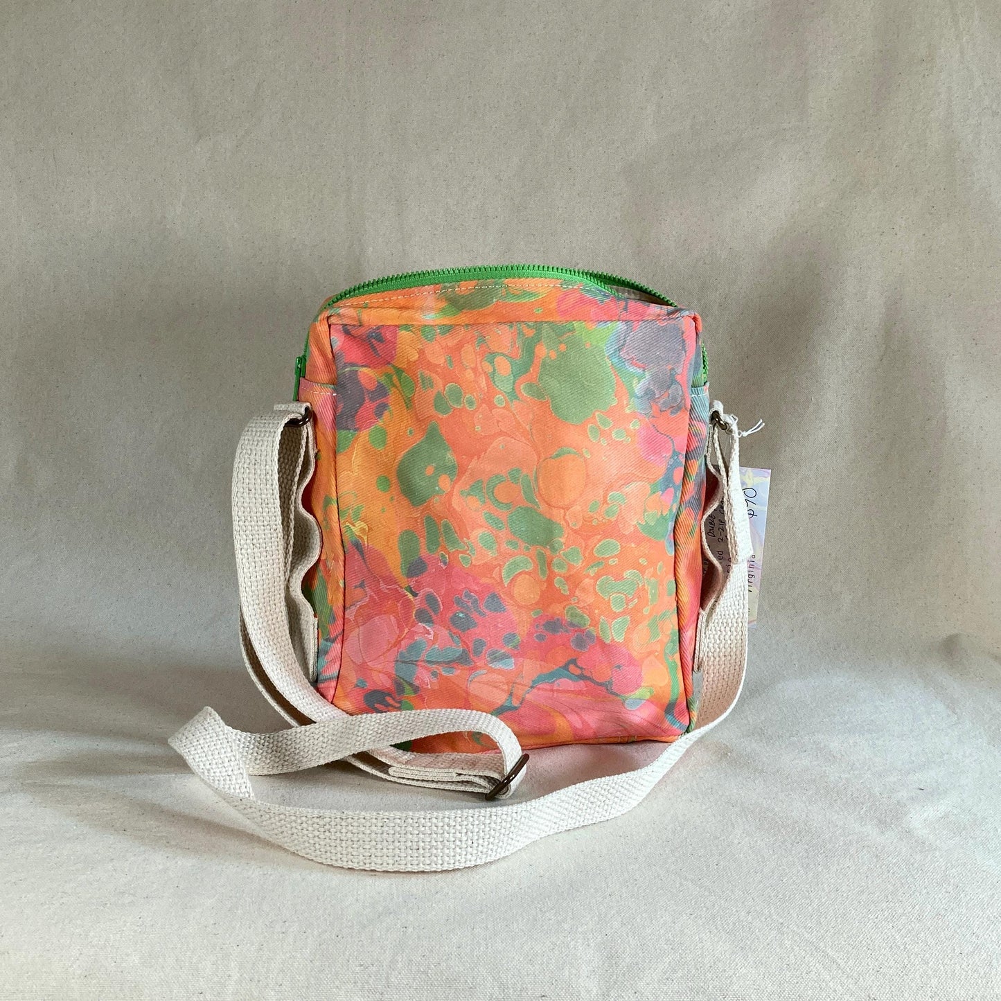 The back of a water marbled zippered crossbody bag