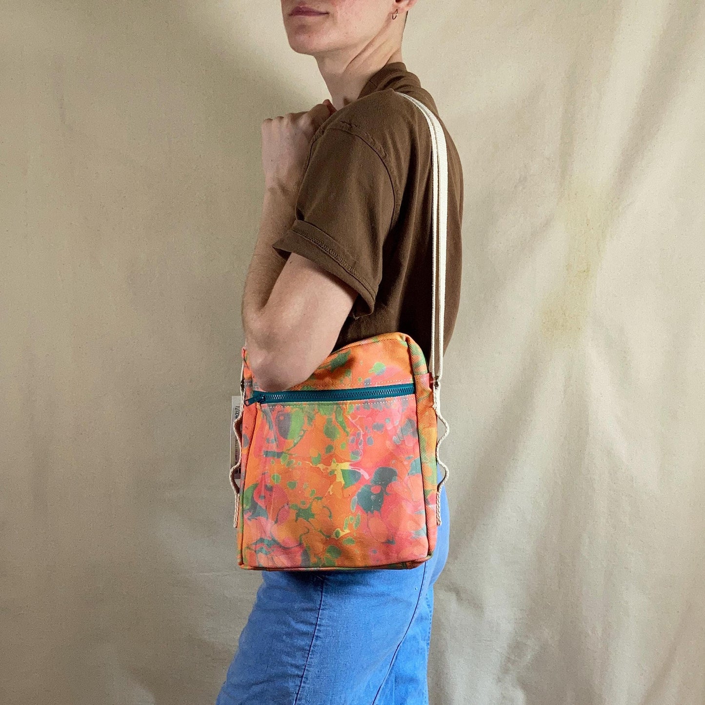 A person modelling a water marbled zippered crossbody bag