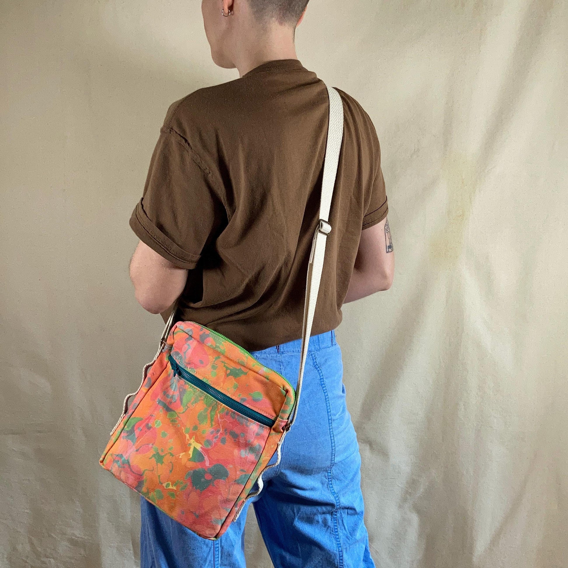 A person modelling a water marbled zippered crossbody bag