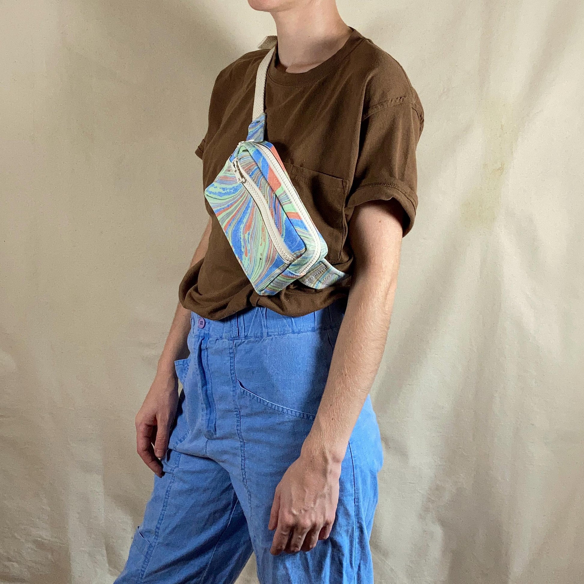 A person modelling a water marbled fanny pack