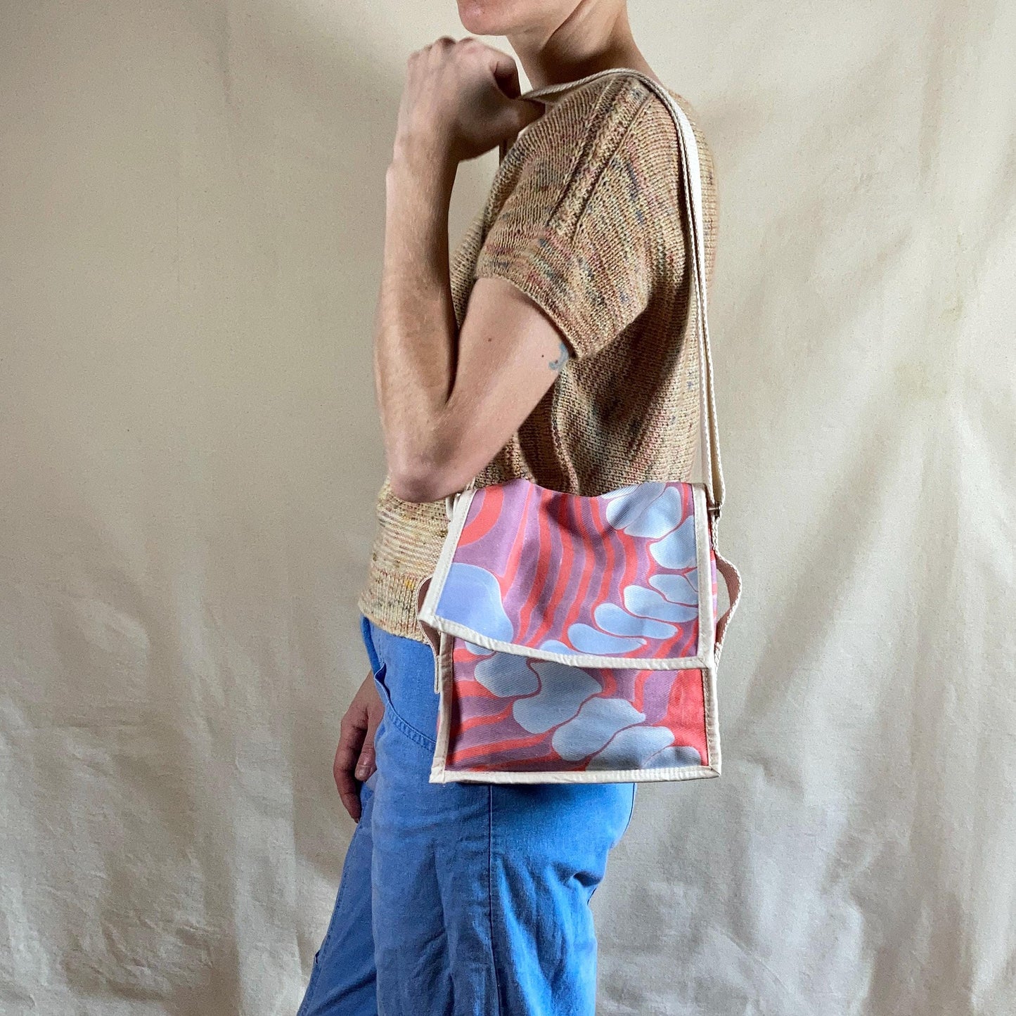 A person modelling a mini square water marbled messenger bag