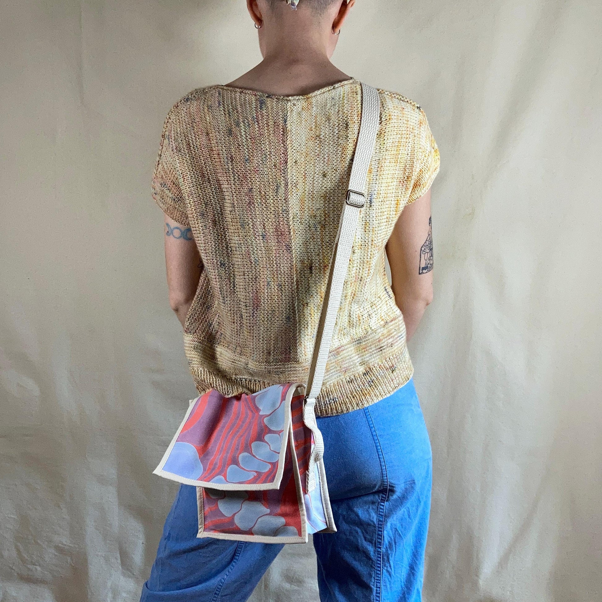 A person modelling a mini water marbled messenger bag