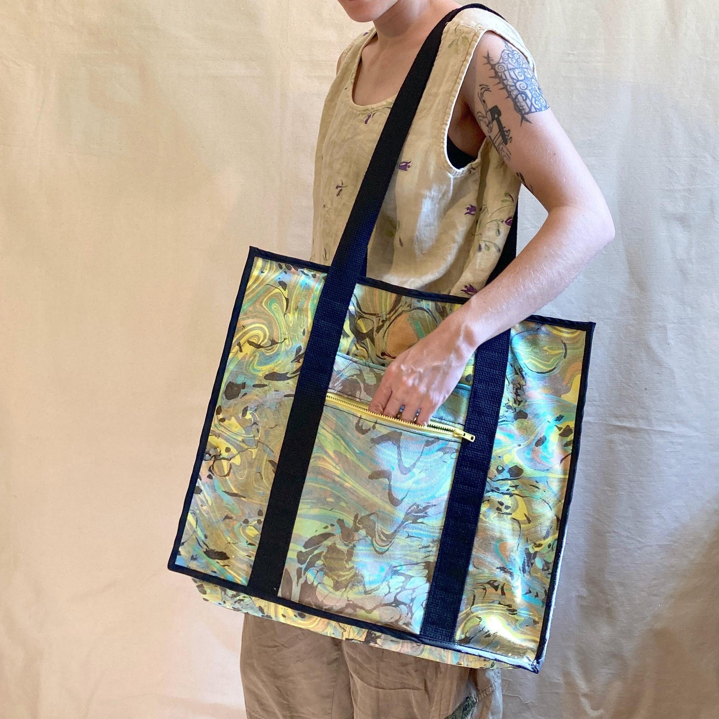 A person modelling an oversized water marbled tote bag with contrasting straps