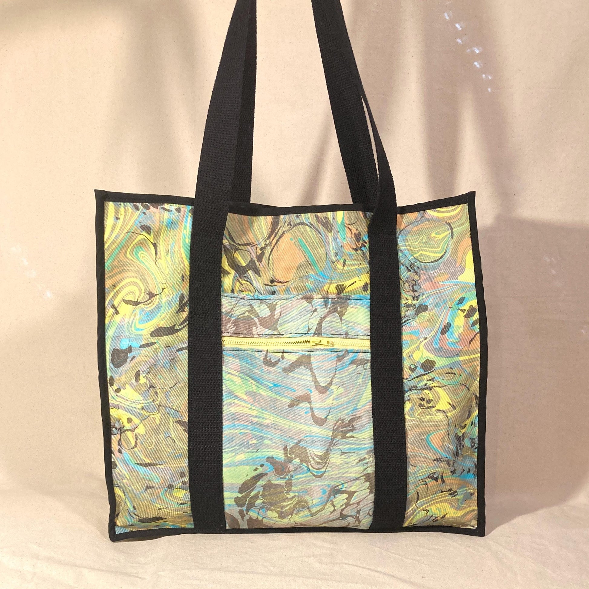 An oversized water marbled tote bag with contrasting straps