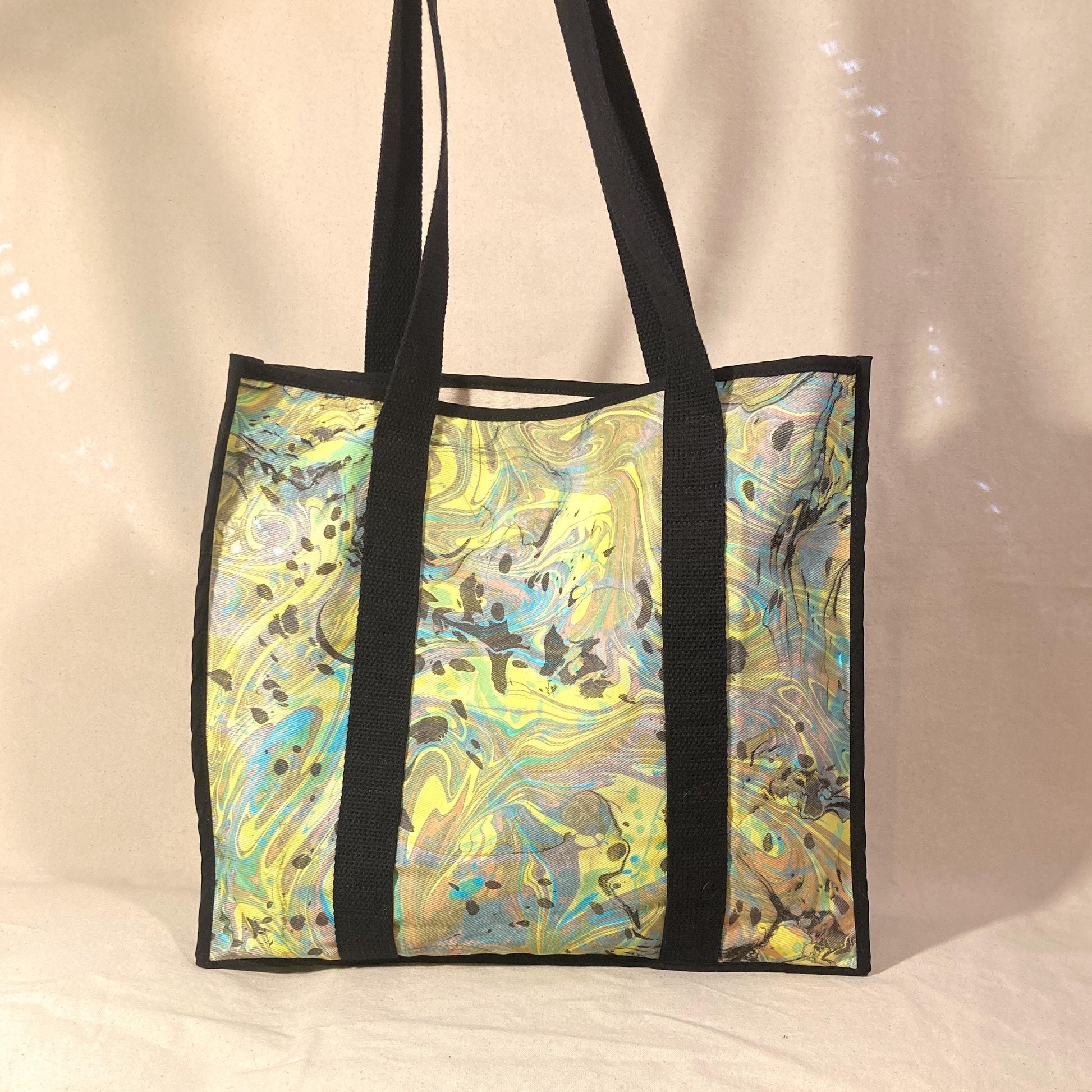 An oversized water marbled tote bag with contrasting straps