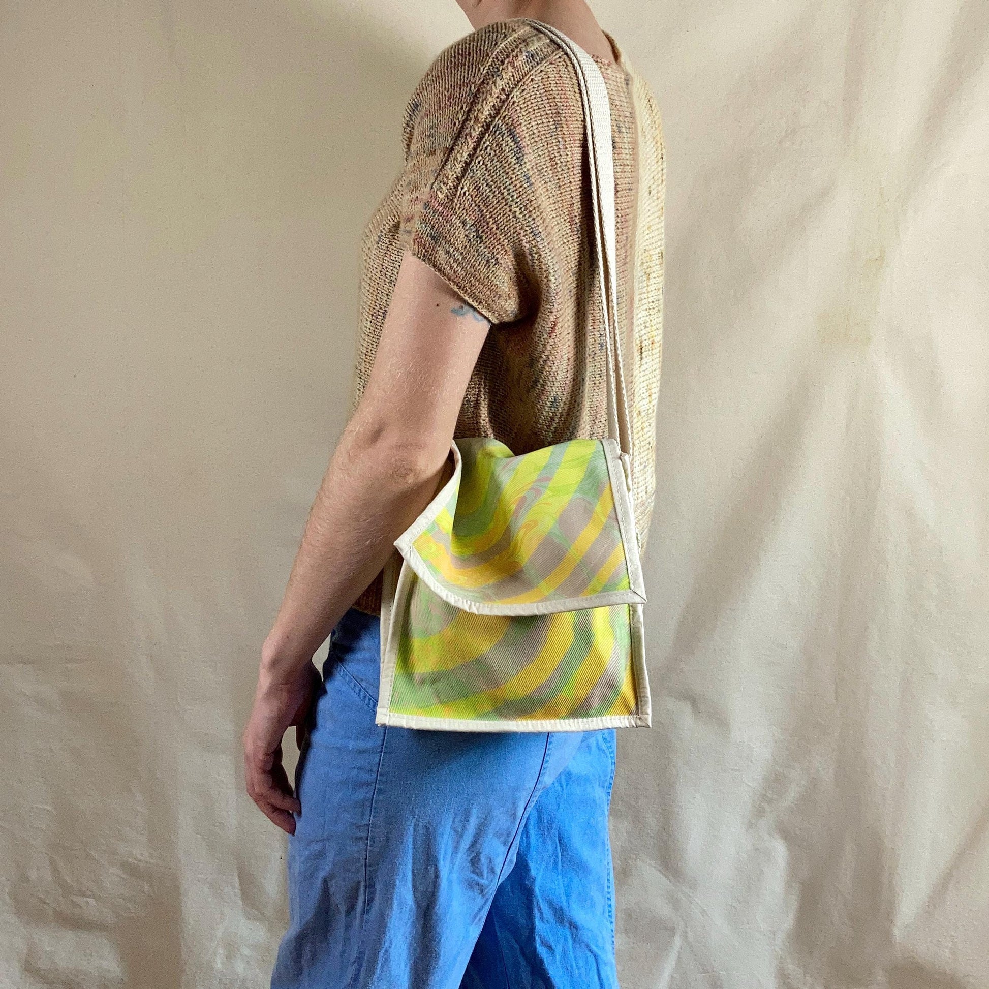 Person modelling a water marbled miniature messenger bag with flap