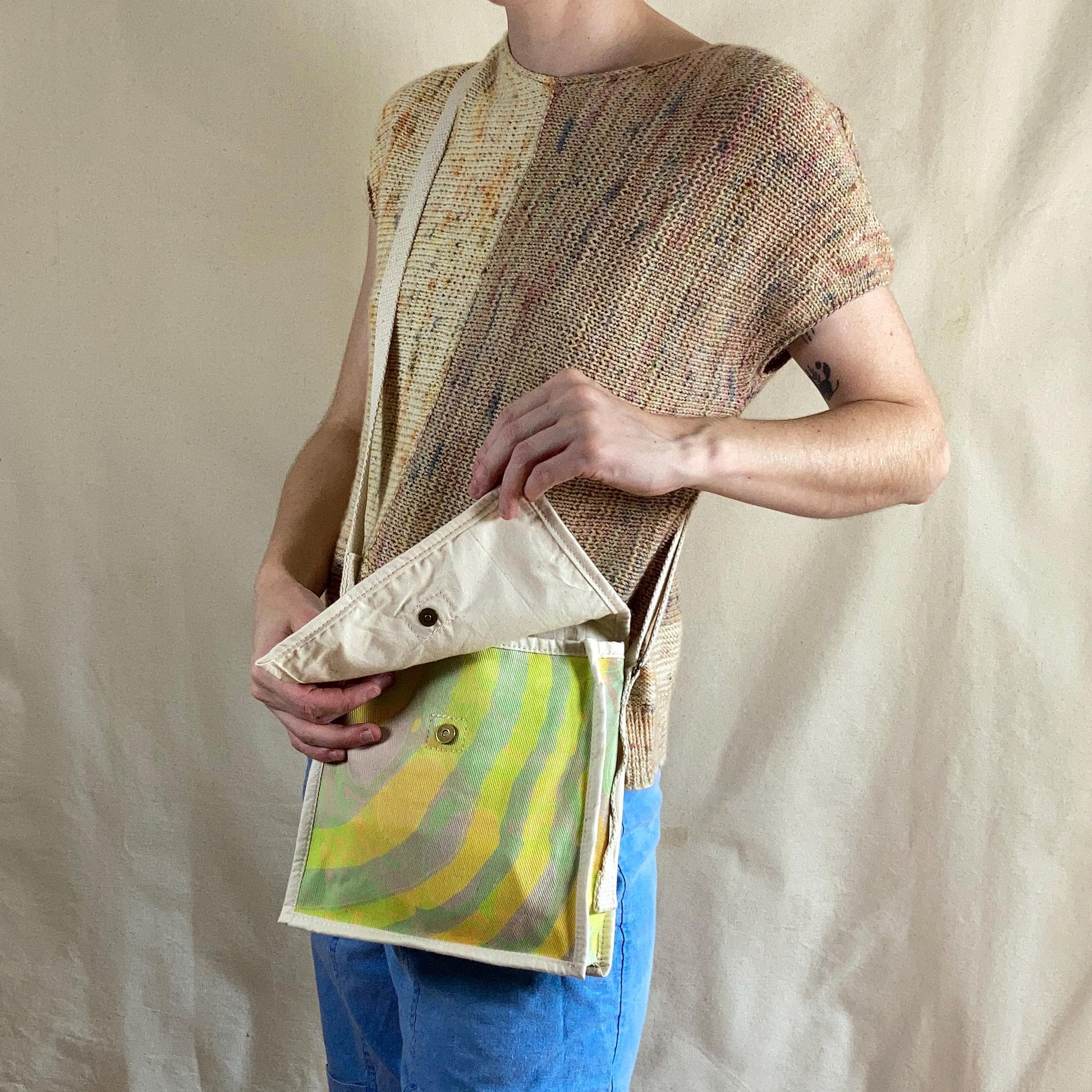 Person modelling a water marbled miniature messenger bag with flap