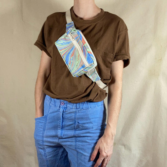 A person modelling a water marbled fanny pack